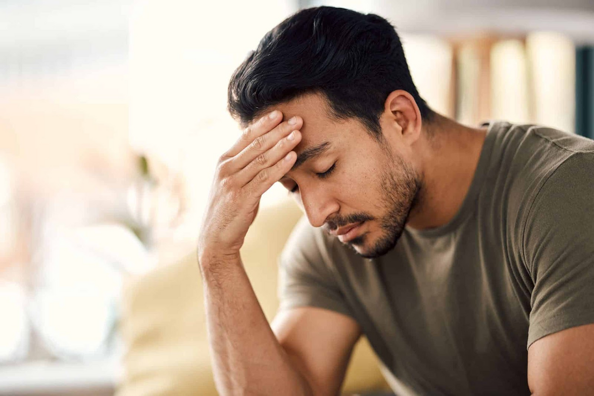 Uomo che si tiene la fronte in un ambiente interno tranquillo, a illustrare il sollievo da stress e ansia
