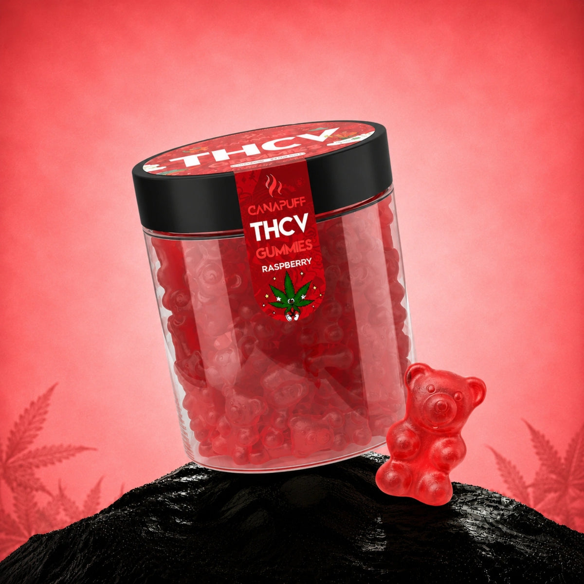 Canapuff THCv Gummies Raspberry in barattolo trasparente con coperchio nero, gummies rosse e un orsetto gommoso accanto su roccia nera